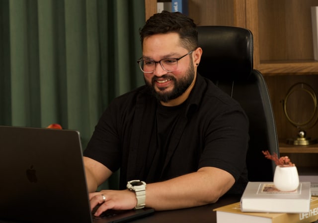 Faris smiling while working at his laptop